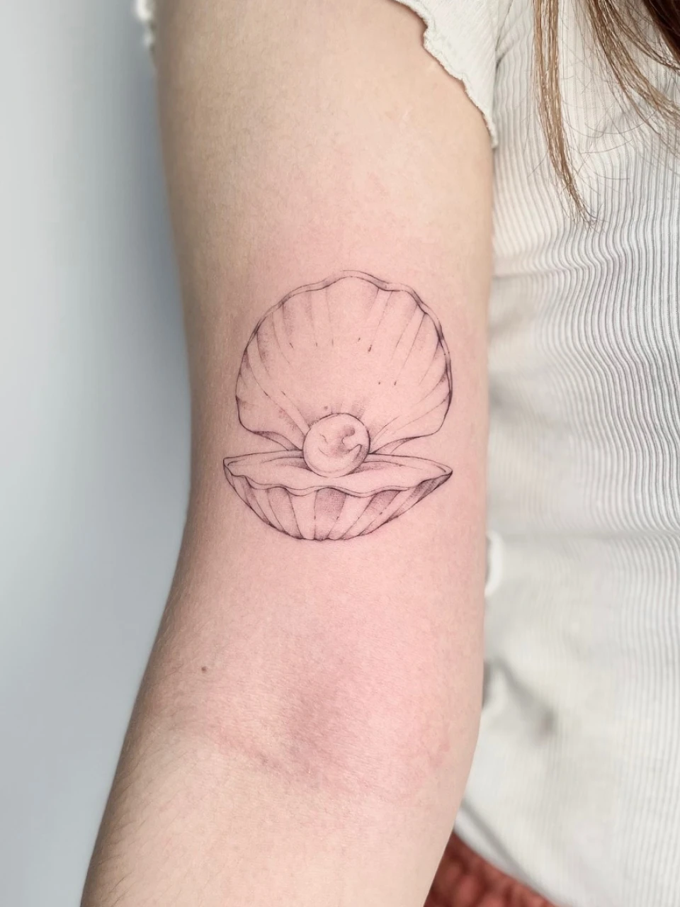 pearl in a shell fine line tattoo on arm